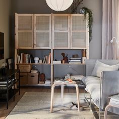 a living room filled with furniture and a book shelf next to a window on top of a hard wood floor