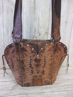 Infuse your look with a dose of Santa Fe style with this one-of-a-kind leather handbag. Hand-crafted from up-crafted cowboy boots and belts. Tote style with no pockets No two alike, signed and numbered Magnetic closure and metal concho detail Measures approximately 10"x12"x5" This exquisite leather bag is more than just a cowboy boot purse - it's a wearable work of art that celebrates the spirit of the American West. Perfect for the lady who wants to infuse her look with a dose of Southwestern s Western Bags With Concho Detail, Western Style Bags With Concho, Western Style Hand Tooled Brown Bag, Western Style Brown Bag With Concho, Western Brown Bag With Adjustable Strap, Hand Tooled Brown Bags For Rodeo, Hand Tooled Brown Bag For Rodeo, Brown Hand Tooled Bag For Rodeo, Western Brown Bags For Rodeo