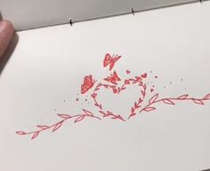 someone is drawing a heart with butterflies on paper