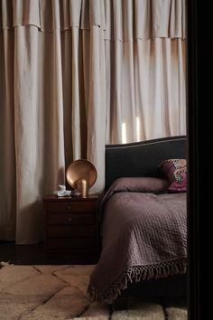 a bed sitting in front of a window with curtains