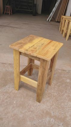 a wooden table sitting on top of a cement floor next to a pile of wood