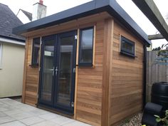 a small wooden building sitting in the middle of a yard with windows on top of it