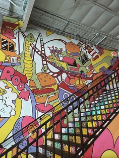 an escalator in front of a colorful mural on the wall