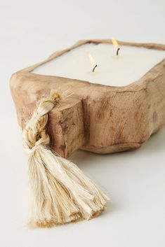 a small white candle sitting on top of a wooden block with a tassel hanging from it