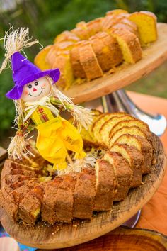 a cake with a doll sitting on top of it next to other cakes and desserts