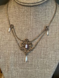 "c1910 Late Art Nouveau gold filled festoon necklace featuring a carved agate cameo set in a scrollwork frame with dog tooth pearl dangles. The piece is in amazing condition. All original. Clasp works well. The setting with cameo and pearl is just shy of 2\" in height. 16.25\" in length. Meant to wrap around the neck." Antique Cameo Necklace, Antique Cabochon Necklaces For Formal Events, Antique Cabochon Necklaces For Formal Occasions, Victorian Jewelry With Antique Finish, Antique Decorative Jewelry For Formal Occasions, Victorian Medallion Jewelry For Vintage Events, Bronze Vintage Charm Necklace For Formal Events, Heirloom Style Brass Necklace With Intricate Design, Elegant Antique Gold Necklace For Collectors