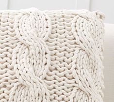 a white knitted pillow sitting on top of a couch