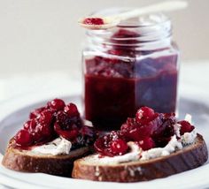 two pieces of bread on a plate with cranberry sauce in a jar next to it