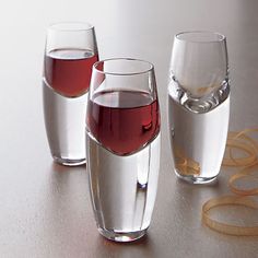 three glasses filled with red wine on top of a table next to another glass full of water