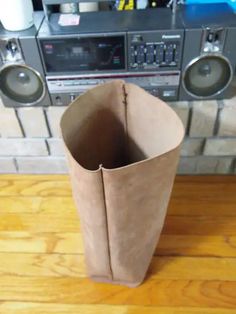 a brown paper bag sitting on top of a wooden table next to a stereo system