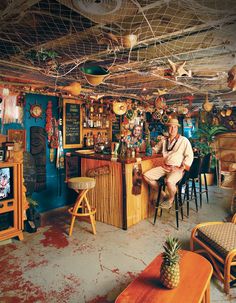 a man sitting at a bar in a room with lots of decorations on the walls