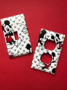 two mickey mouse light switch covers on a red surface with black and white designs,