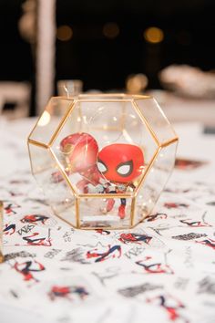 a glass vase filled with red and yellow balls on top of a tablecloth covered table