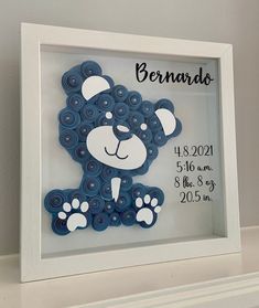 a baby's birth announcement with a blue teddy bear in a frame on a shelf