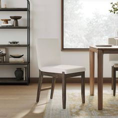 a dining room table with two chairs and a vase on top of the table next to it