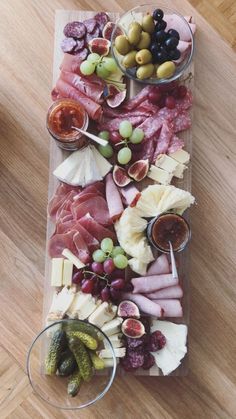 a platter filled with meats, cheeses and olives on a wooden table