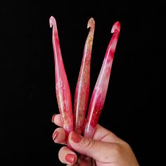 a person holding up some pink and gold fake toothbrushes