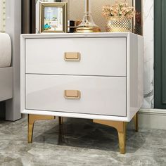 a white chest of drawers with gold handles and knobs on top in a living room