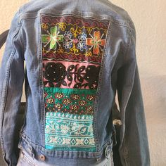 the back of a woman's jean jacket with embroidered flowers on it