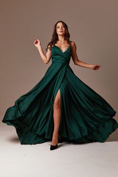 a woman in a long green dress posing for the camera with her legs spread out