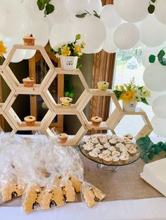 a dessert table with cupcakes, cookies and other treats on it in front of balloons