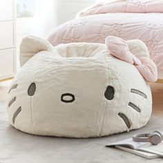 a white cat shaped bed sitting on top of a floor next to a pink comforter