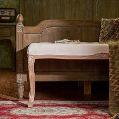 a wooden bench sitting on top of a rug next to a table with a lamp