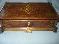 an ornate wooden box with gold trimmings sits on a blue cloth covered table