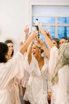 a group of women in robes toasting with wine glasses on their heads as they hold up champagne flutes