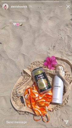 the contents of a beach bag are laid out in the sand with flowers and sunscreen