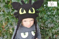 a young boy wearing a crocheted hat with ears and eyes on his head