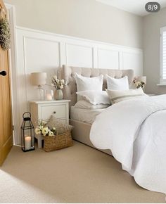 a bed with white linens and pillows in a bedroom next to a wooden door