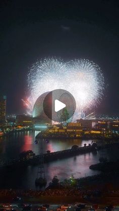 fireworks are lit up in the night sky over a river and cityscape with buildings