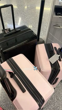 three pieces of luggage sitting on top of an airport baggage claim carousel, one pink and one black