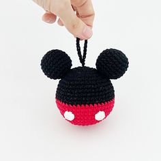 a hand holding a crocheted mickey mouse ornament in black, red and white