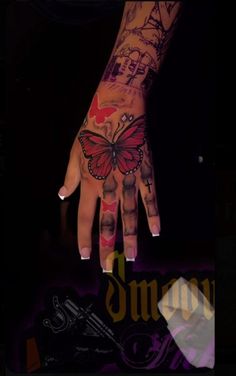 a woman's hand with tattoos on it and a butterfly painted on the palm