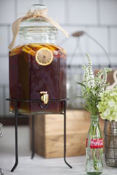 a glass jar filled with liquid sitting on top of a table next to vases