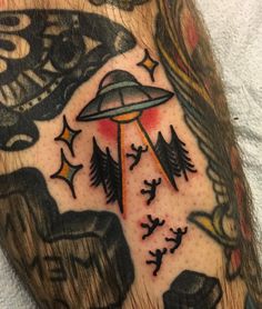 a man's arm with tattoos on it and an alien flying through the sky