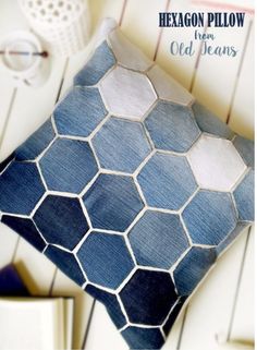 a blue and white pillow sitting on top of a wooden table next to a book