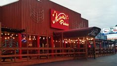 an outside view of a restaurant with red walls and lights on the side of it