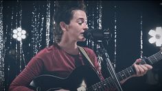 a man with dreadlocks playing an acoustic guitar in front of a microphone and lights