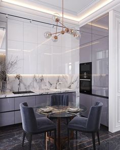 a modern kitchen with marble counter tops and white cabinets, along with blue chairs around a round glass table