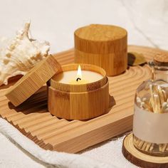 a candle sitting on top of a wooden tray next to shells and seashells