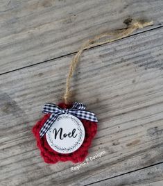 a red ornament hanging from a string on a wooden floor with a tag that says noel