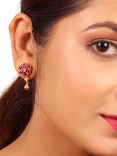 Crafted from 925 silver with a polished gold finish, this earring showcases an elegant and minimalistic Rosana stud (rose) design. It is adorned with vibrant red kemp and white kundan stones, accompanied by enchanting ball dangles that enhance its delightful and beautiful appeal. Ideal for daily wear, the Rosana stud adds a charming touch to your everyday attire. Please refer to the pictures of the jewelry worn on a model to get a clear idea of the size. Condition: New. This product is intricately designed and meticulously handcrafted with exceptional care by our skilled silversmiths, employing traditional Indian techniques. Every jewelry piece from Sashastrends bears a 925-hallmark stamp! Earring closure: Screw back. Material: 925 silver (gold polish), red kemp, white kundan stones. Place Dual-tone Bridal Earrings As Gift, Festive Rose Gold Earrings For Gift, Traditional Rose Gold Earrings For Gift, Traditional Rose Gold Earrings For Celebration, Elegant Dual-tone Bridal Earrings As Gift, Elegant Dual-tone Bridal Earrings For Gift, Elegant Dual-tone Bridal Earrings, Kundan Earrings For Puja, Elegant Earrings For Diwali Puja