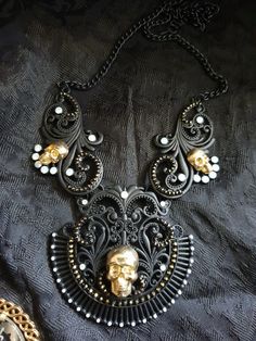 Stylized vintage matte black necklace with brass skulls. All crystals are original and intact and have a beautiful opalescent shimmer. The skulls are brass stampings. As this is a new kind of item for me to be selling in my store I'm listing it for a special INTRODUCTORY OFFER. This listing is for the necklace ONLY. This item is a 1 of a kind design.  The item shown in this listing is the item you will be purchasing so please look at the photos carefully before purchasing. This listing is for th Gothic Metal Skull Necklace, Handmade Black Steampunk Necklace, Handmade Gothic Skull Necklace, Steampunk Black Necklace For Halloween, Unique Black Halloween Necklace, Black Gothic Jewelry With Skull Print, Gothic Black Brass Necklace, Black Gothic Brass Necklace, Black Steampunk Jewelry For Halloween