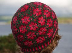 a close up of a person wearing a red and green knitted beanie hat