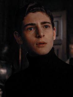 a young man in a black turtle neck sweater looking at the camera with an intense look on his face