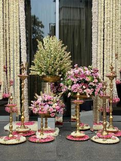 there are many vases with flowers in them on the street side, one is gold and the other is pink