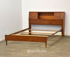 a wooden bed frame sitting on top of a hard wood floor next to a white wall